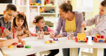 Happy teacher enjoying with group of children at preschool.