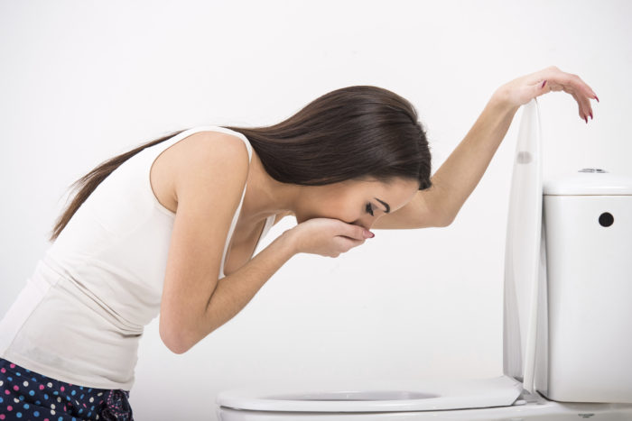 A woman about to vomit in the toilet