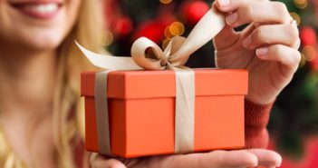 Portrait of beautiful young woman opening presents on Christmas day.