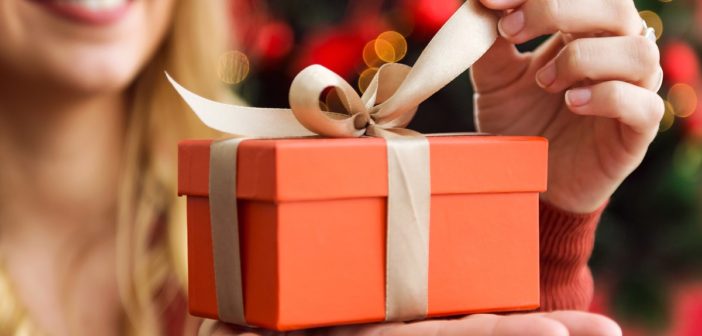 Portrait of beautiful young woman opening presents on Christmas day.