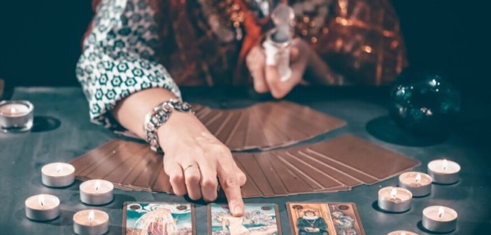 Fortune,Teller,With,Tarot,Cards,On,Table,Near,Burning,Candles.tarot